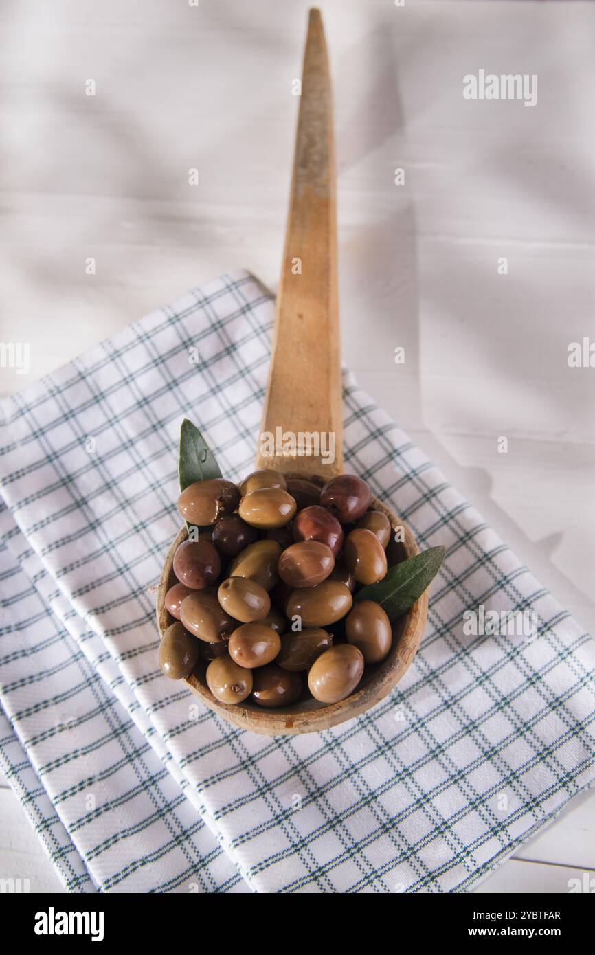 Präsentation einer kleinen Gruppe schwarzer Oliven auf Holzpfanne Stockfoto