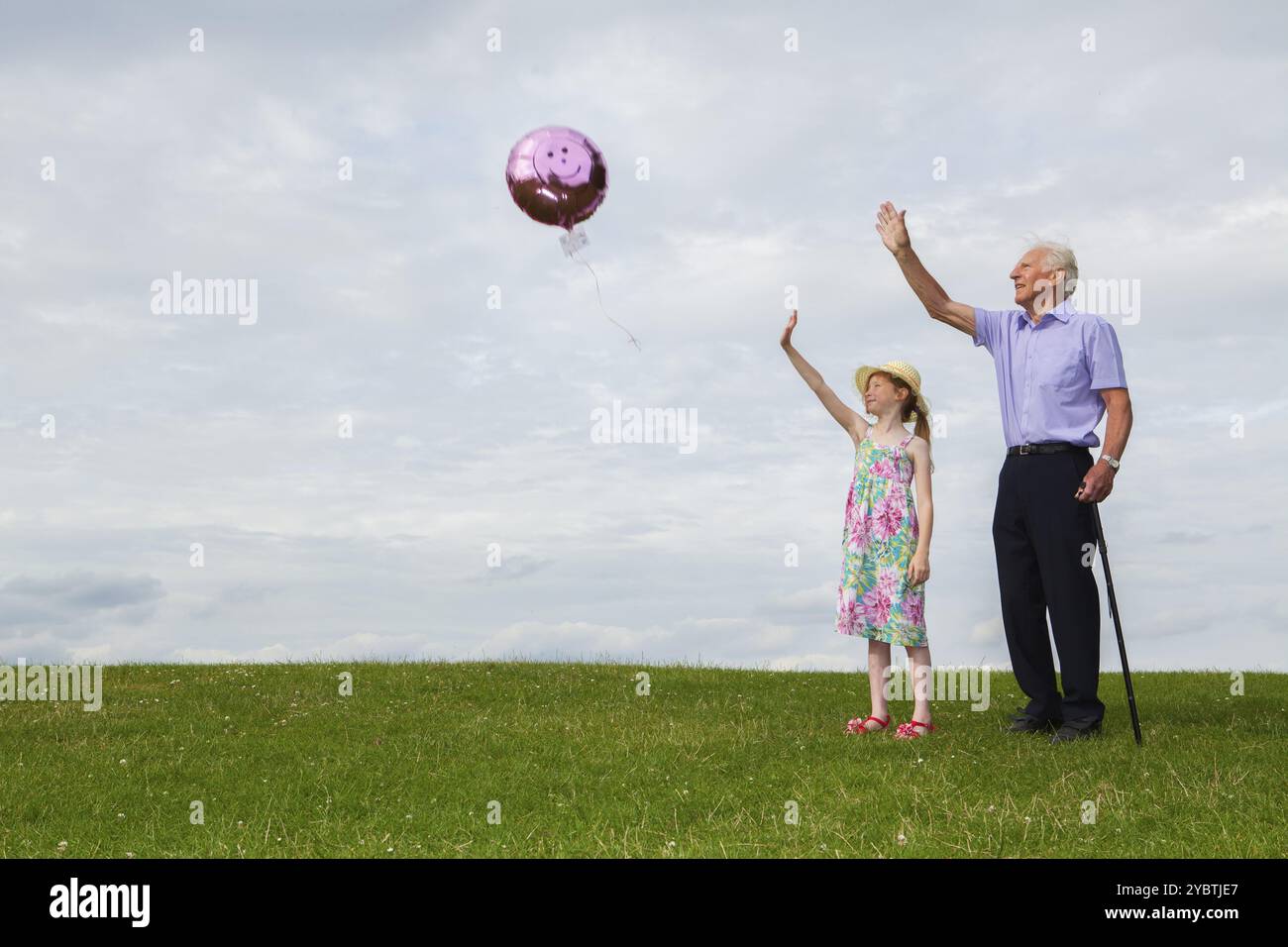 Weißes Mädchen und ihr Großvater lassen einen Heliumballon in den Himmel los Themen der Freiheit Abschiedstraum Stockfoto