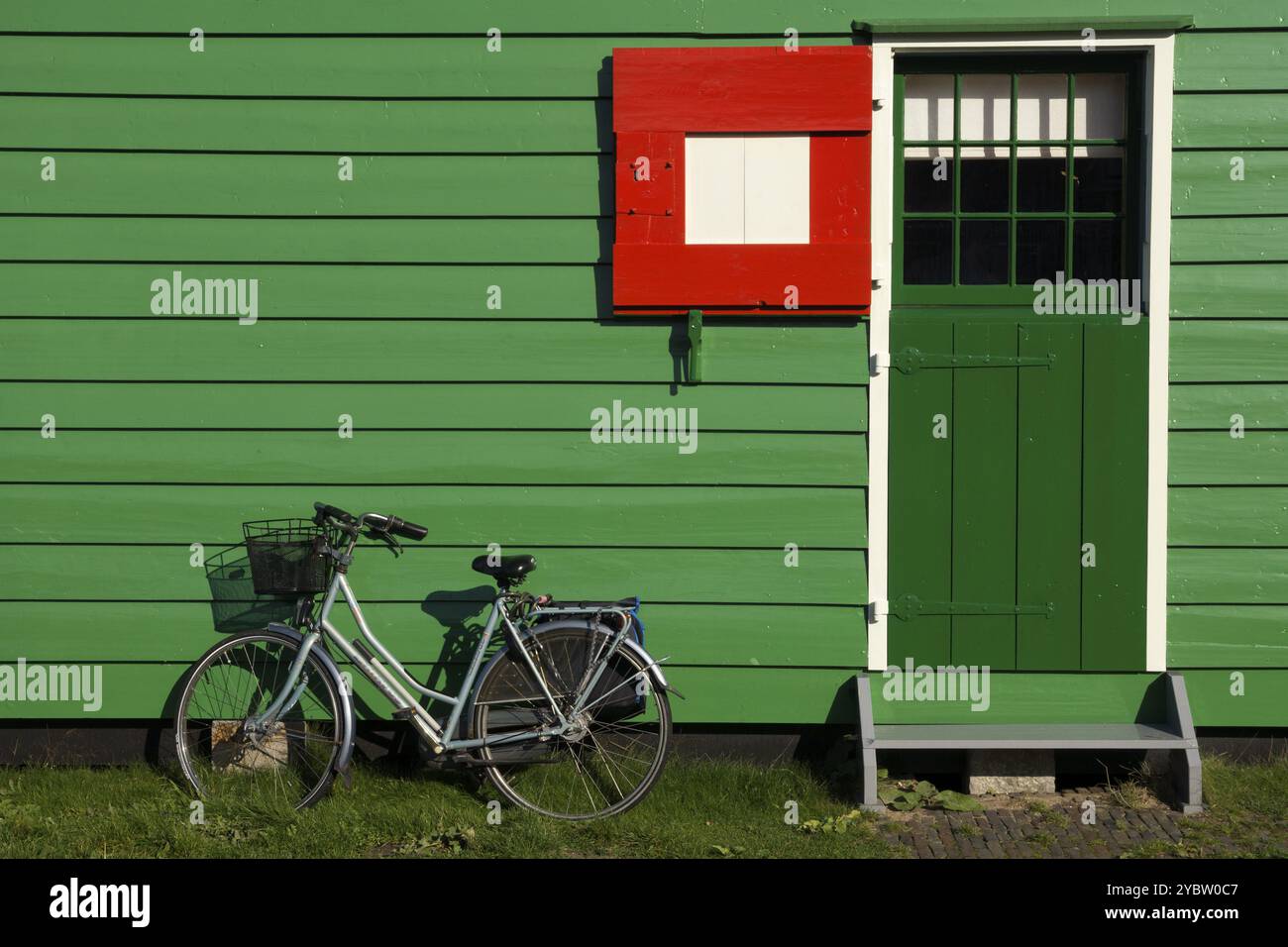 Fahrrad parkt vor einem grün bemalten Fachwerkhaus auf der niederländischen Touristenattraktion Zaanse Schans Stockfoto