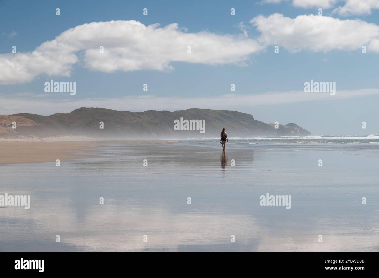 Einzeltourist am Strand von Farewell Spit und genießt die Aussicht auf das Meer und die umliegenden Hügel (Südinsel, Neuseeland) Stockfoto