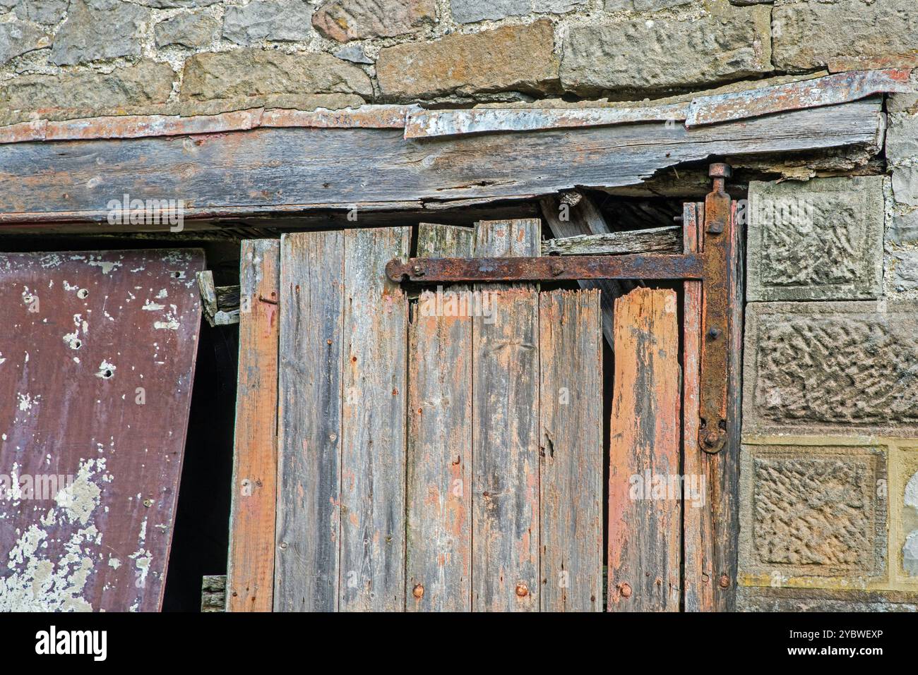 Eine alte und zertrümmerte Scheunentür, die von den rostigen Scharnieren in Derbyshire, England, hängt Stockfoto