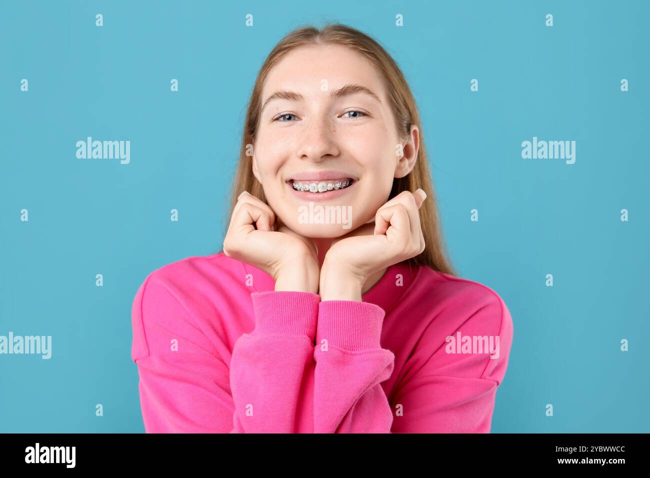 Lächelndes Mädchen mit Zahnspangen auf hellblauem Hintergrund Stockfoto