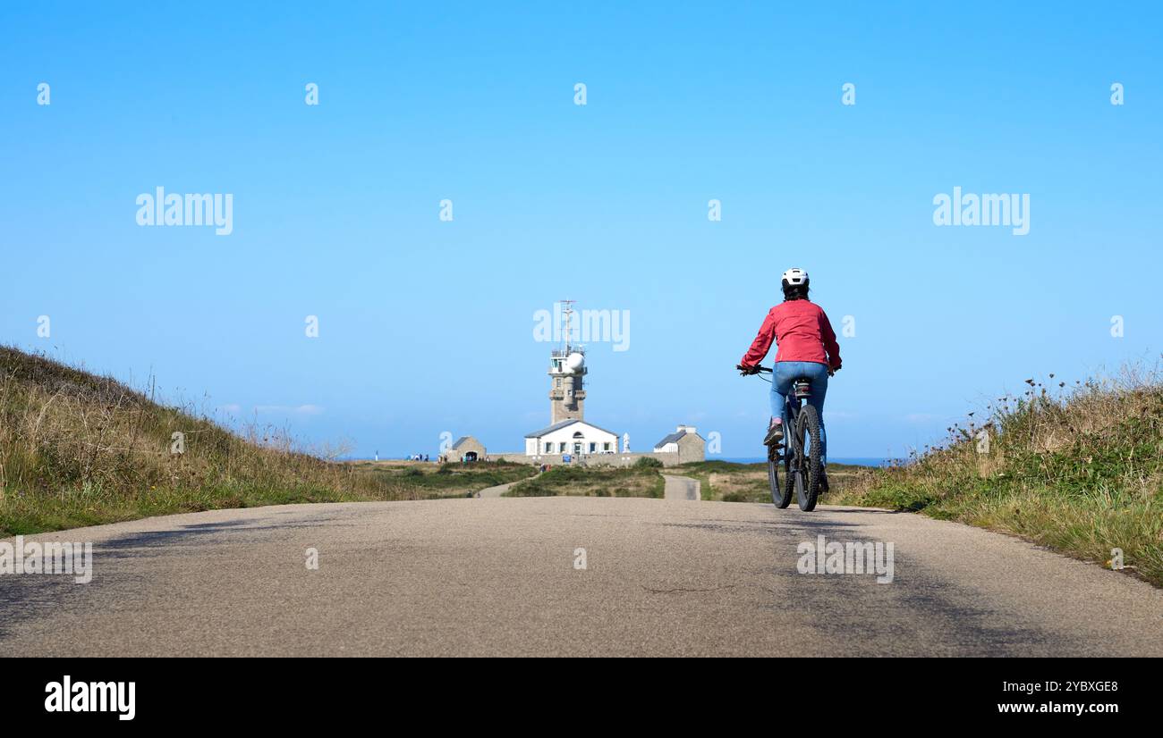 Aktive Seniorin radelt mit ihrem E-Mountainbike am cape Pointe de Raz, Finistere, Bretagne, Frankreich Stockfoto