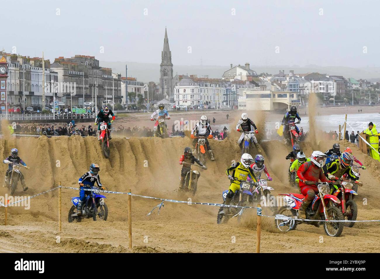 Weymouth, Dorset, Großbritannien. Oktober 2024. Mehr als 300 Fahrer, die von Tausenden von Zuschauern beobachtet werden, nehmen am 40. Motocross-Rennen in Weymouth Beach Teil, auf einem provisorischen Golfplatz, der von Baggern aus dem goldenen Sand des Resorts geschnitzt wurde. Die jährliche kostenlose Veranstaltung wird vom Purbeck Motocross Club veranstaltet. Bildnachweis: Graham Hunt/Alamy Live News Stockfoto