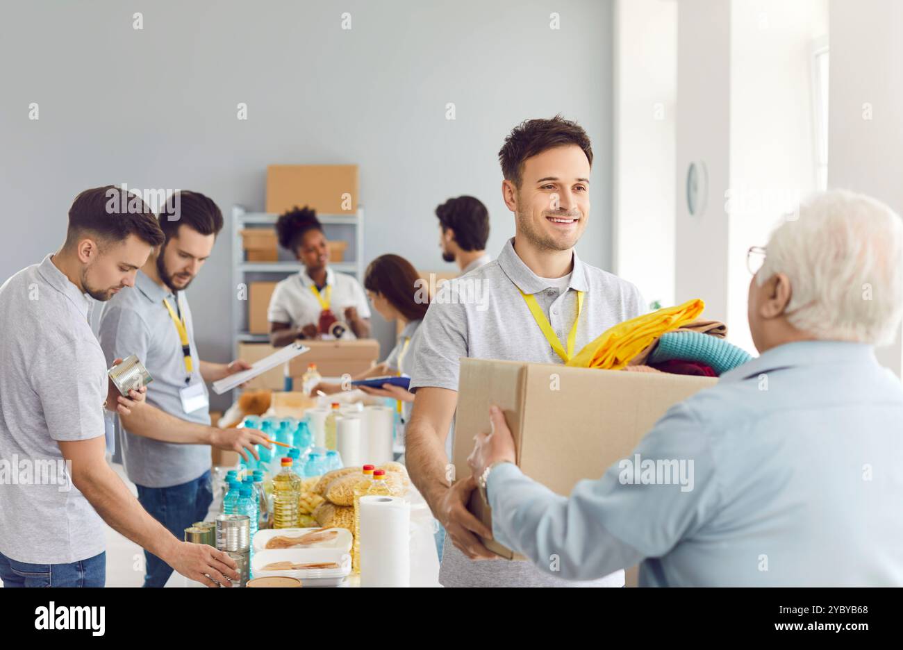 Volunteer Handing Food Box To Elderly Man At Humanitarian Aid Center Stockfoto