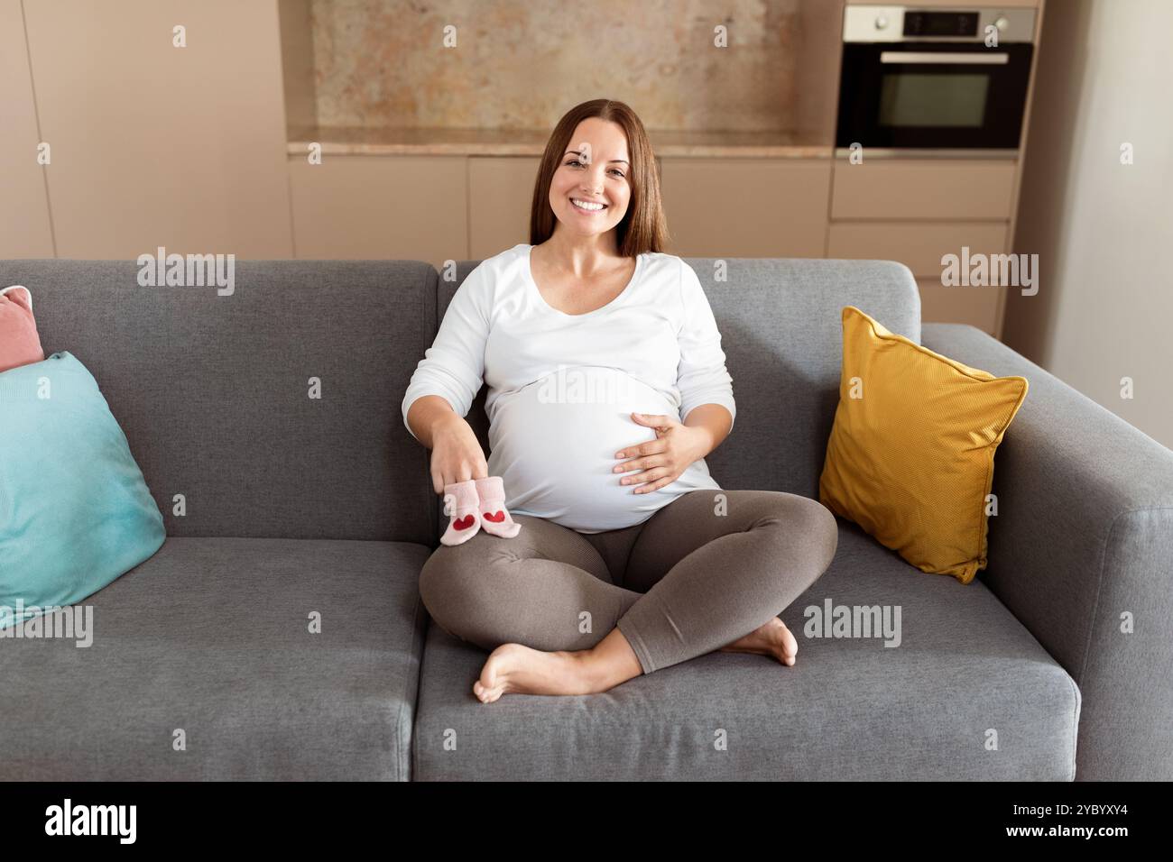 Die werdende Mutter sitzt bequem auf einem Sofa in einem modernen Zuhause Stockfoto