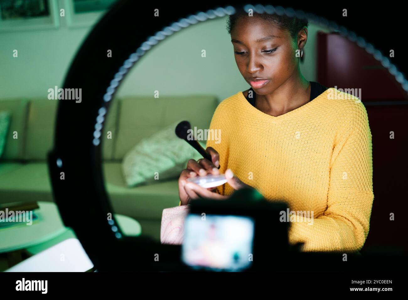 Eine Frau erstellt ein Make-up-Tutorial, das eine Ringleuchte für eine ideale Beleuchtung während des Filmens verwendet Stockfoto