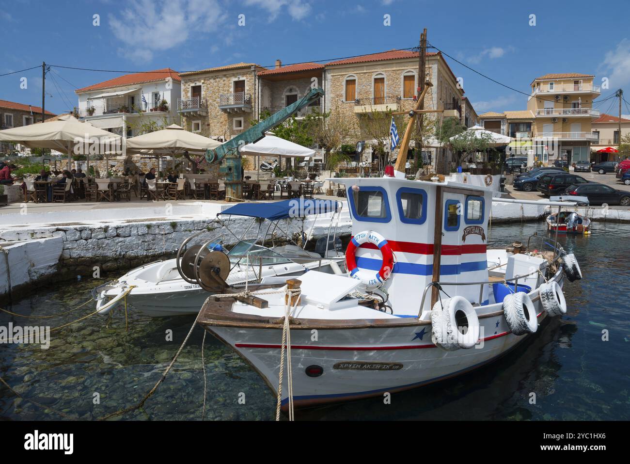 Traditionelle Fischerboote im Hafen vor einer Küstenstadt mit historischen Gebäuden, Agios Nikolaos, Mani, Messenia, Peloponnes, Griechenland, Euro Stockfoto