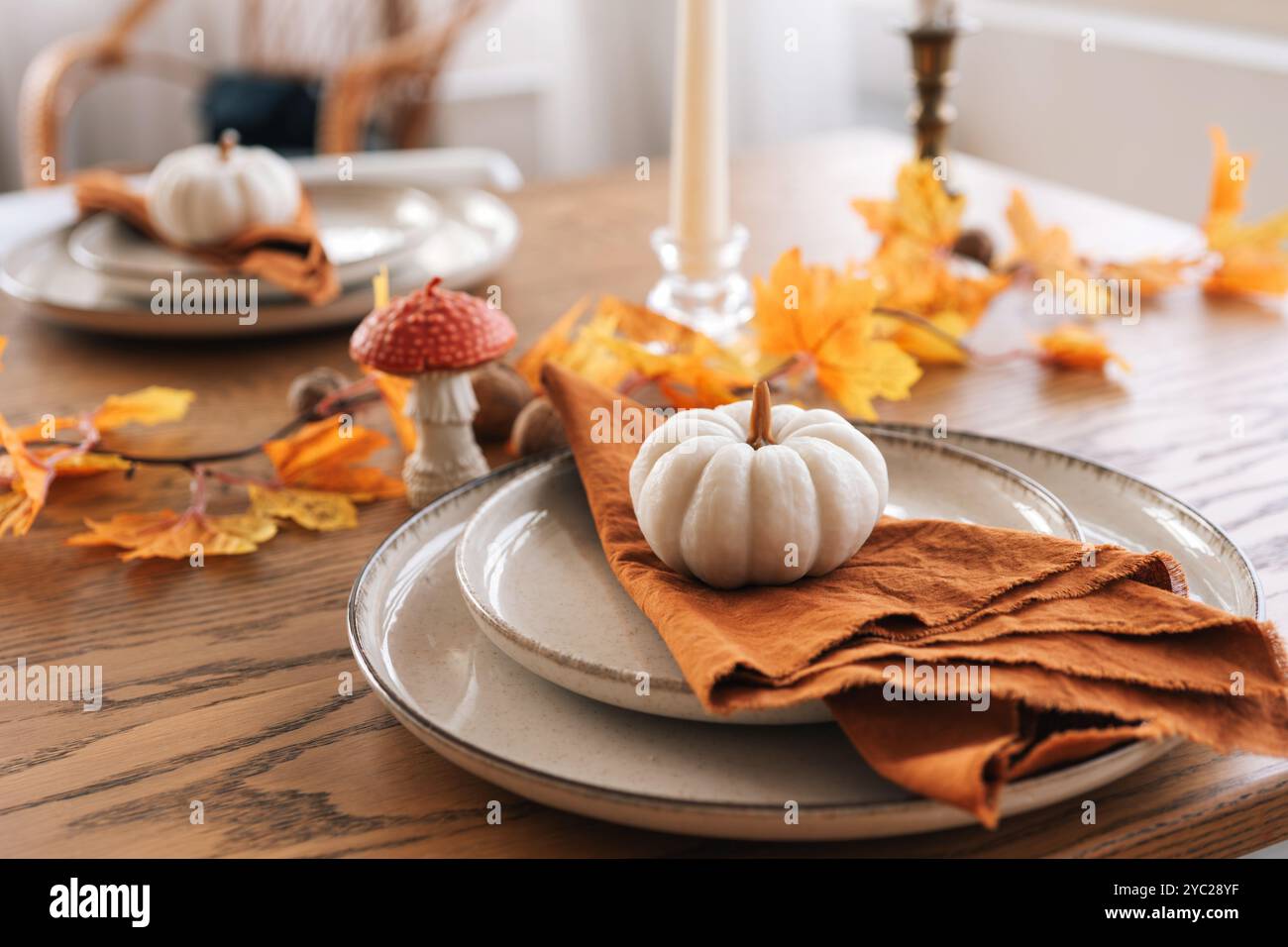 Herbst, Herbst, Halloween oder Thanksgiving festliche Tischdekoration. Gefallene Blätter, Kürbisse und Servietten auf Teller auf Holztischhintergrund. Stockfoto