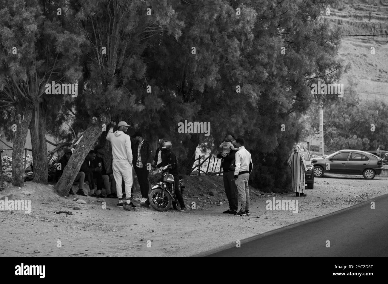 Eine Gruppe von Freunden unterhält sich neben der großartigen Oase Tafilalet in Marokko, Nordafrika. Die größte Oase der Welt. Der Ziz-Fluss in der Mitte des des Stockfoto