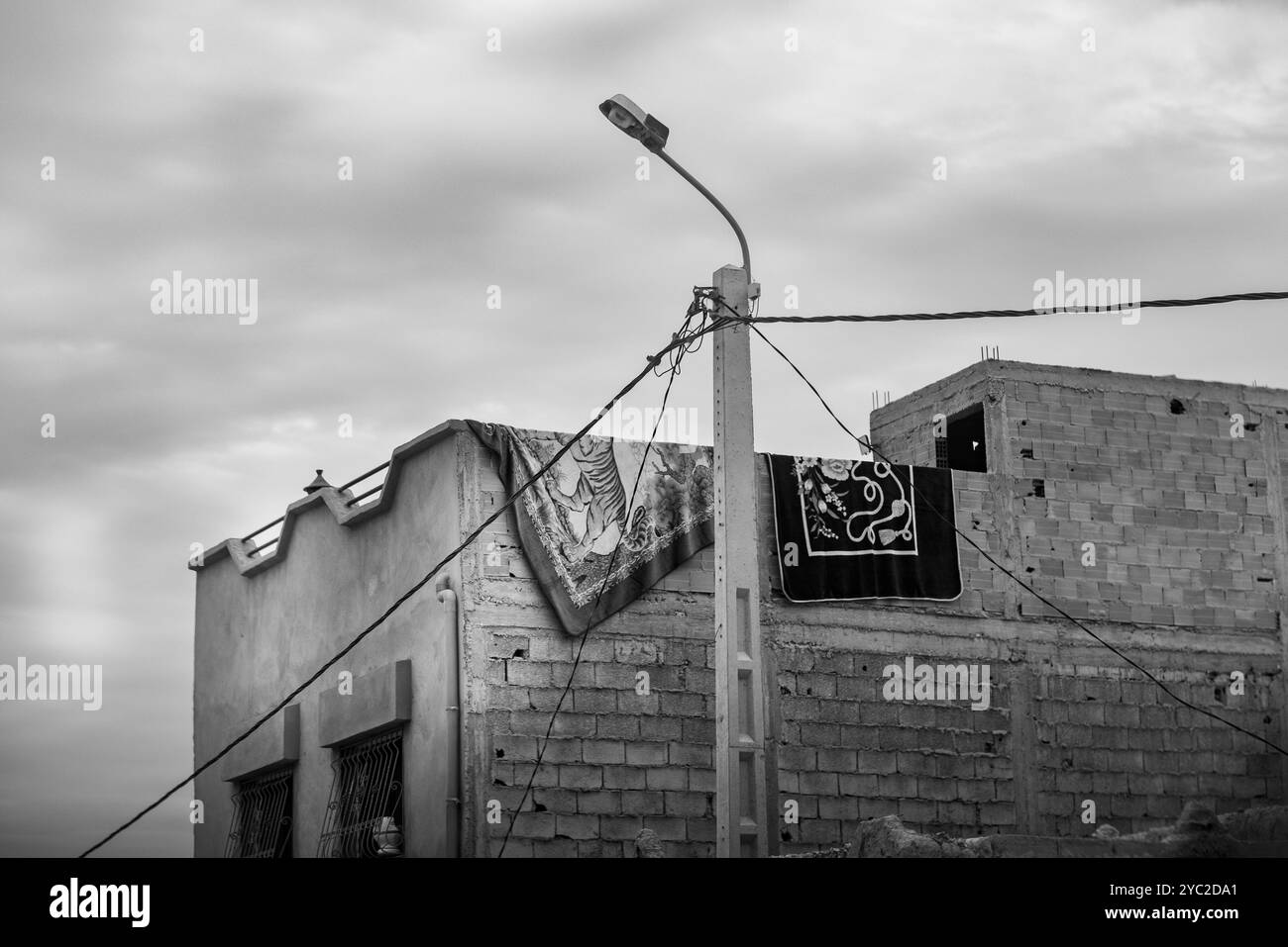 Das Dach eines Hauses in Marokko, Nordafrika. Es besteht aus Zement und Ziegeln und zwei riesigen Teppichen, die an der oberen Wand lufttrocken sind Stockfoto