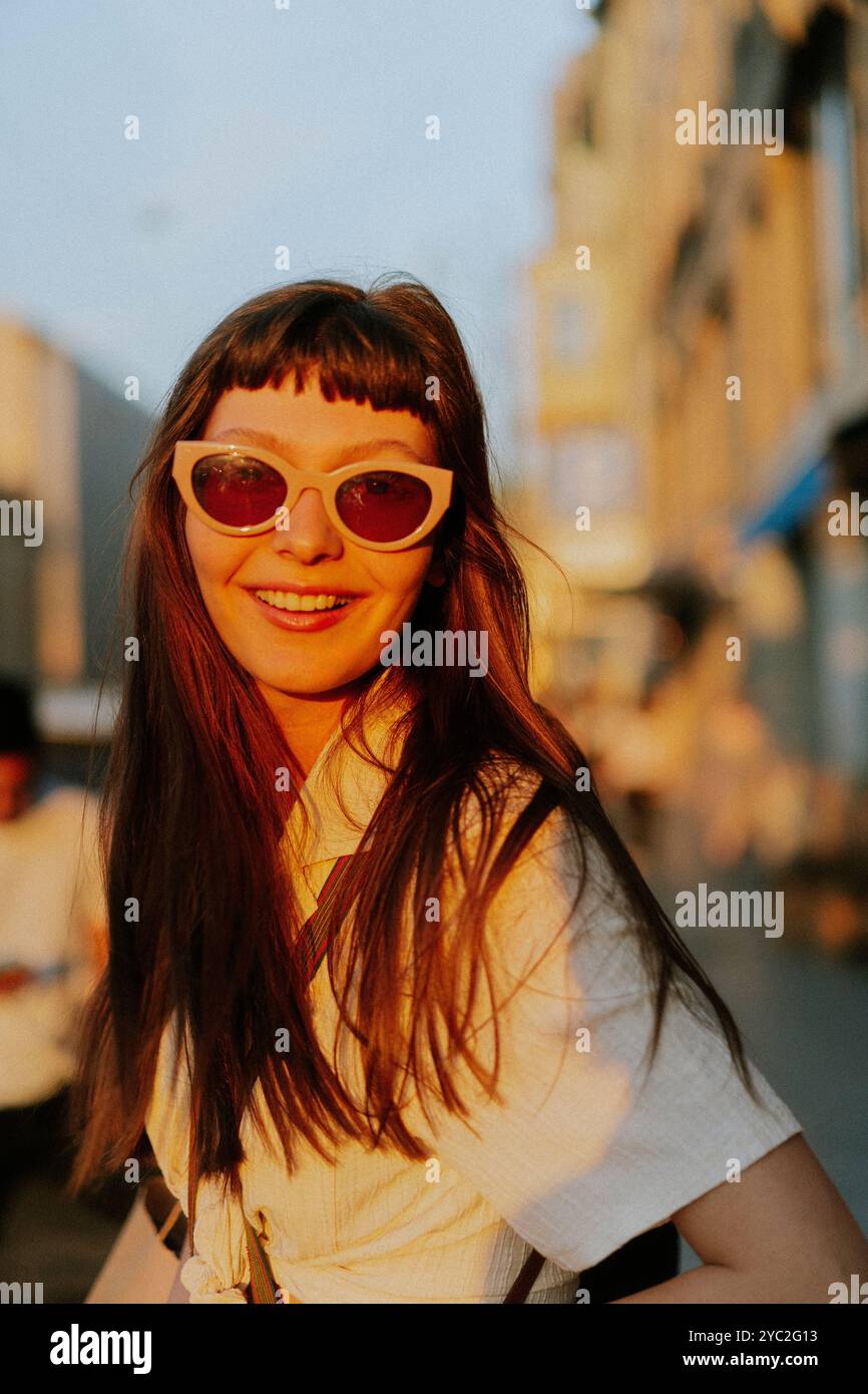 Glückliche lächelnde Frau, die an sonnigem Tag in der Stadt steht. Stockfoto