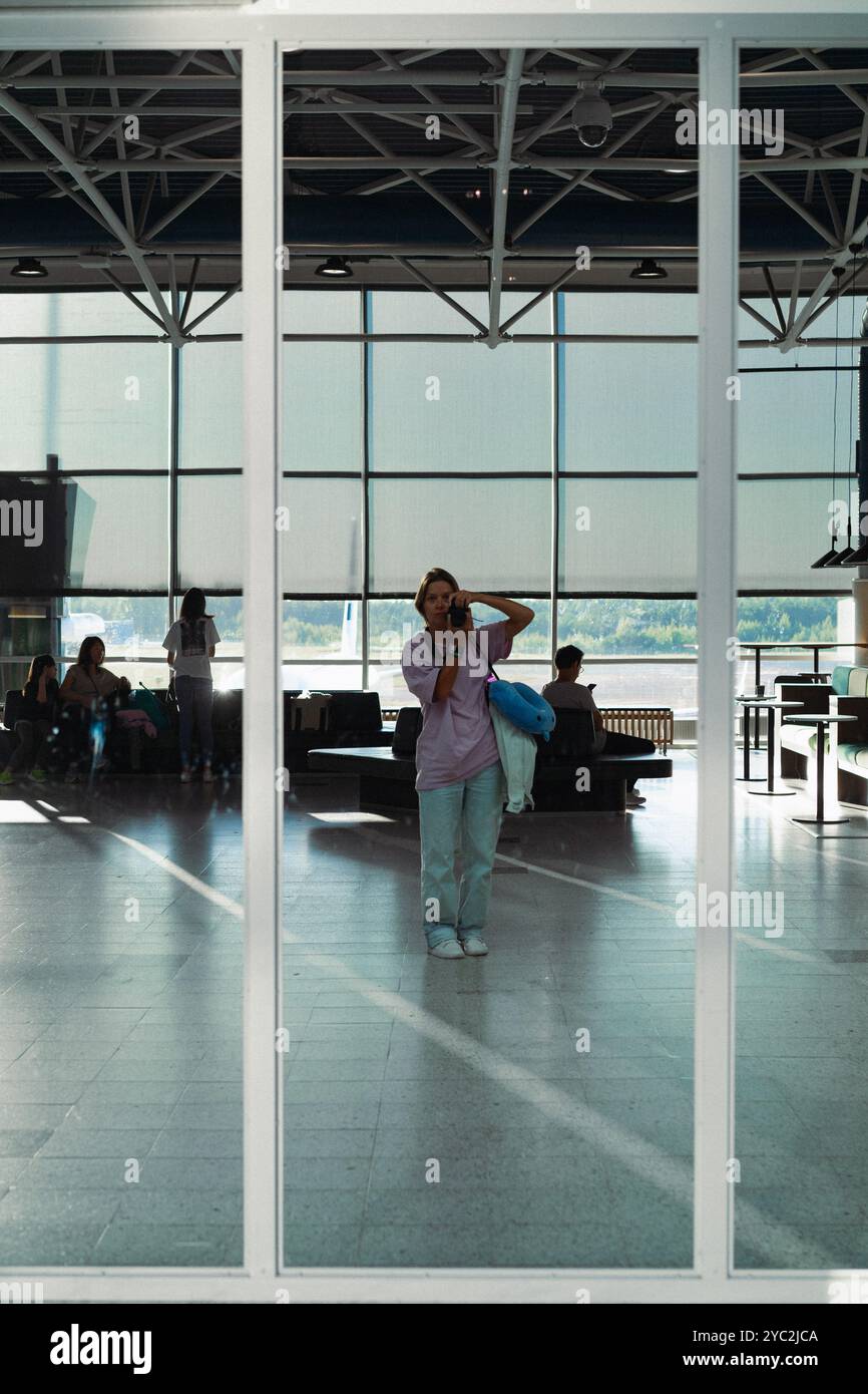 Eine junge Frau am Flughafen macht ein Foto im Spiegel Stockfoto