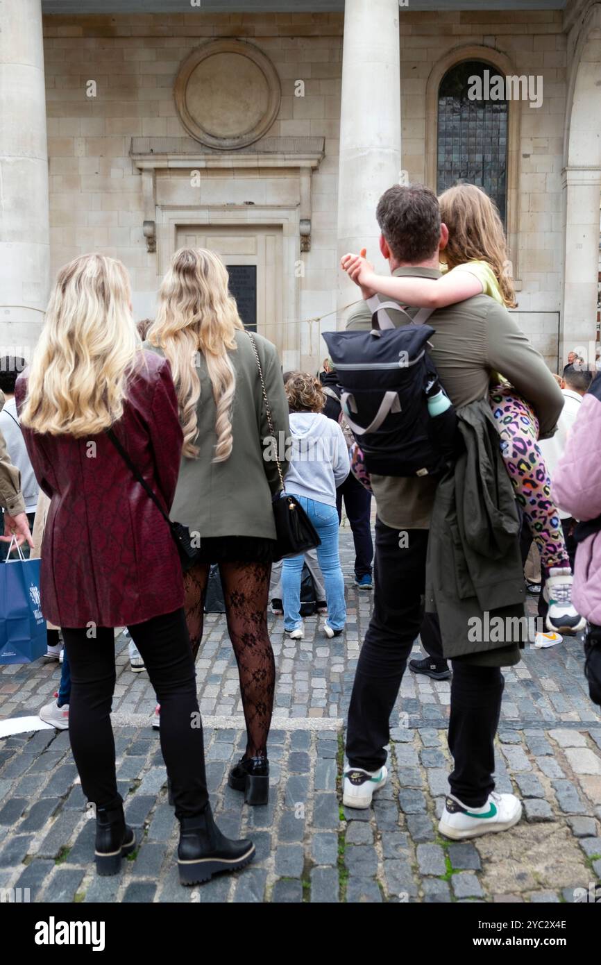 Rückansicht von hinten Familientouristen beobachten Straßenunterhalter auf dem Covent Garden Market im Herbst Oktober 2024 London England Großbritannien KATHY DEWITT Stockfoto