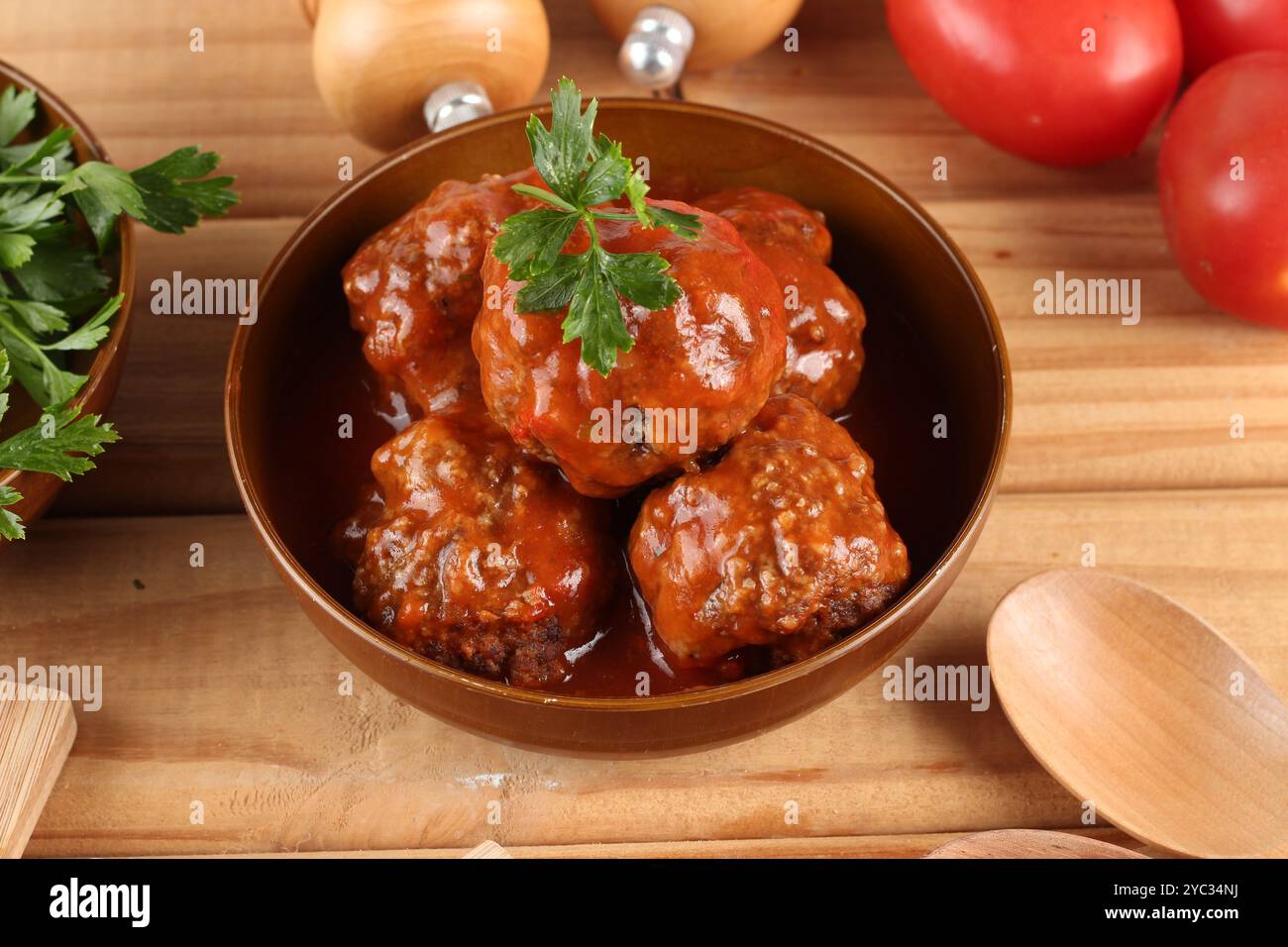 Fleischbällchen mit Tomatensoße auf einem Teller serviert und mit Petersilie garniert Stockfoto