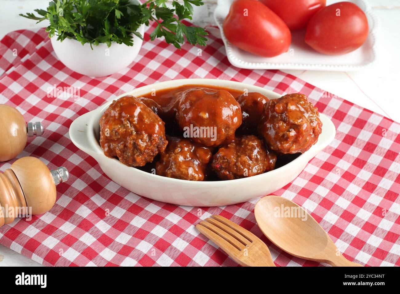 Fleischbällchen mit Tomatensoße auf einem Teller serviert und mit Petersilie garniert Stockfoto