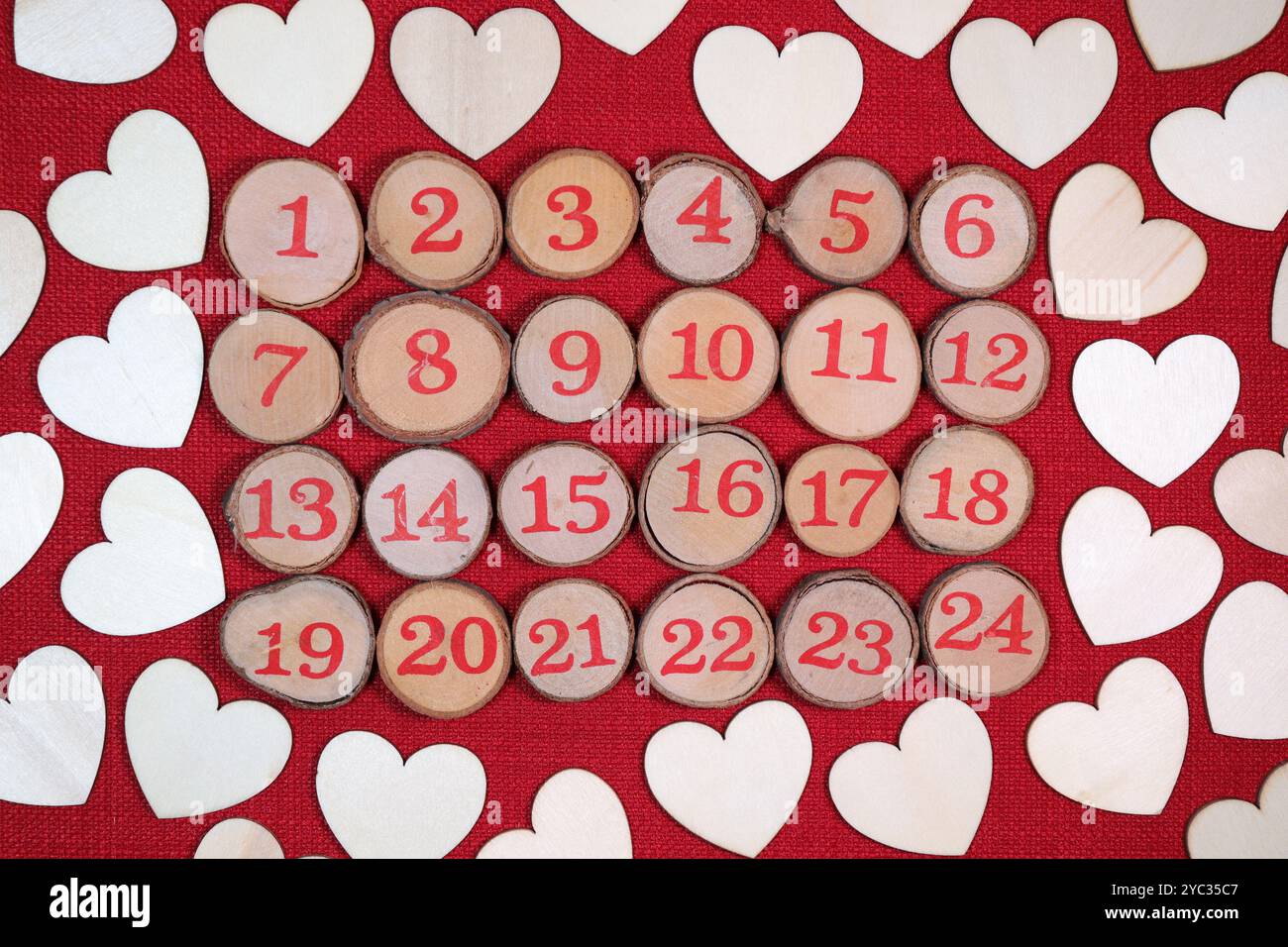 Hölzerner WeihnachtsAdvent, 1 bis 24 weihnachtlicher Countdown, umgeben von hölzernen Liebesherzen, vor rotem Stich Hintergrund. Stockfoto