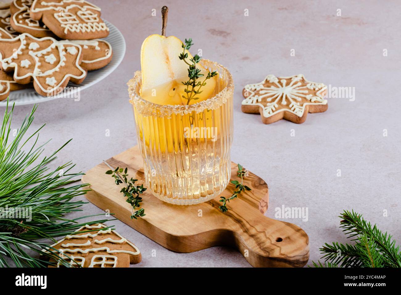 Erfrischender Cocktail mit Birne, Thymian und einem Zimtstab, serviert auf einem Holzbrett in modernem Ambiente mit Keksen. Festlicher Cocktail. Hoher ph-Wert Stockfoto