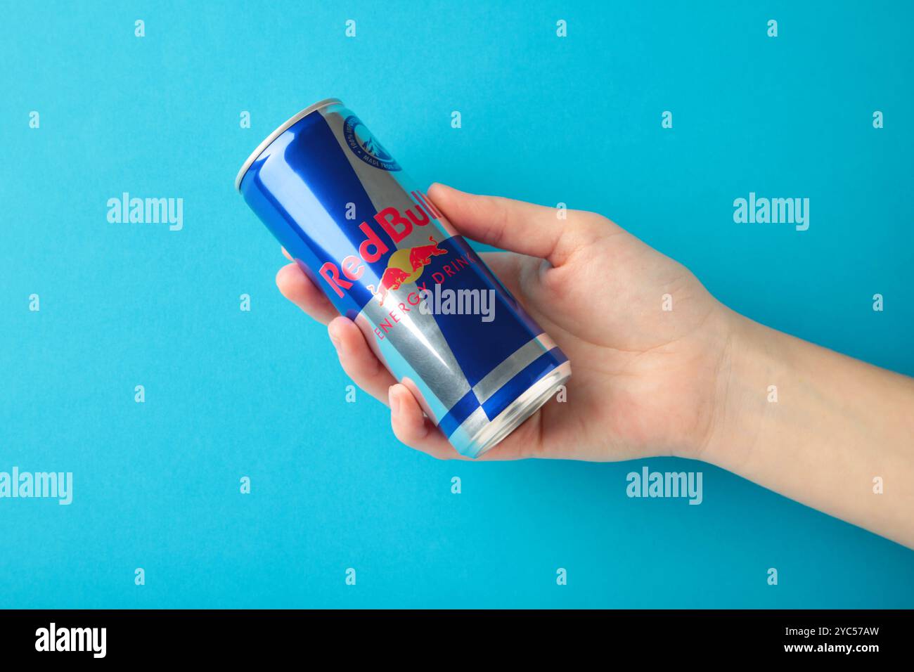 Mykolaiv, Ukraine - 2. Mai 2023: Hand hält eine Dose Red Bull Energy Drink auf blauem Hintergrund. Red Bull ist der beliebteste Energy Drink der Welt Stockfoto