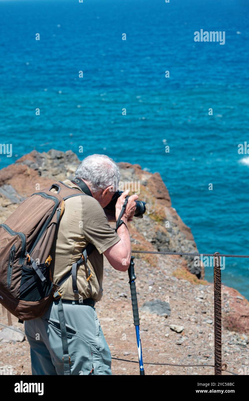 Älterer Fotograf mit Blick auf den atemberaubenden Blick auf das Meer von den Klippen von Vereda da Ponta de São Lourenco Stockfoto