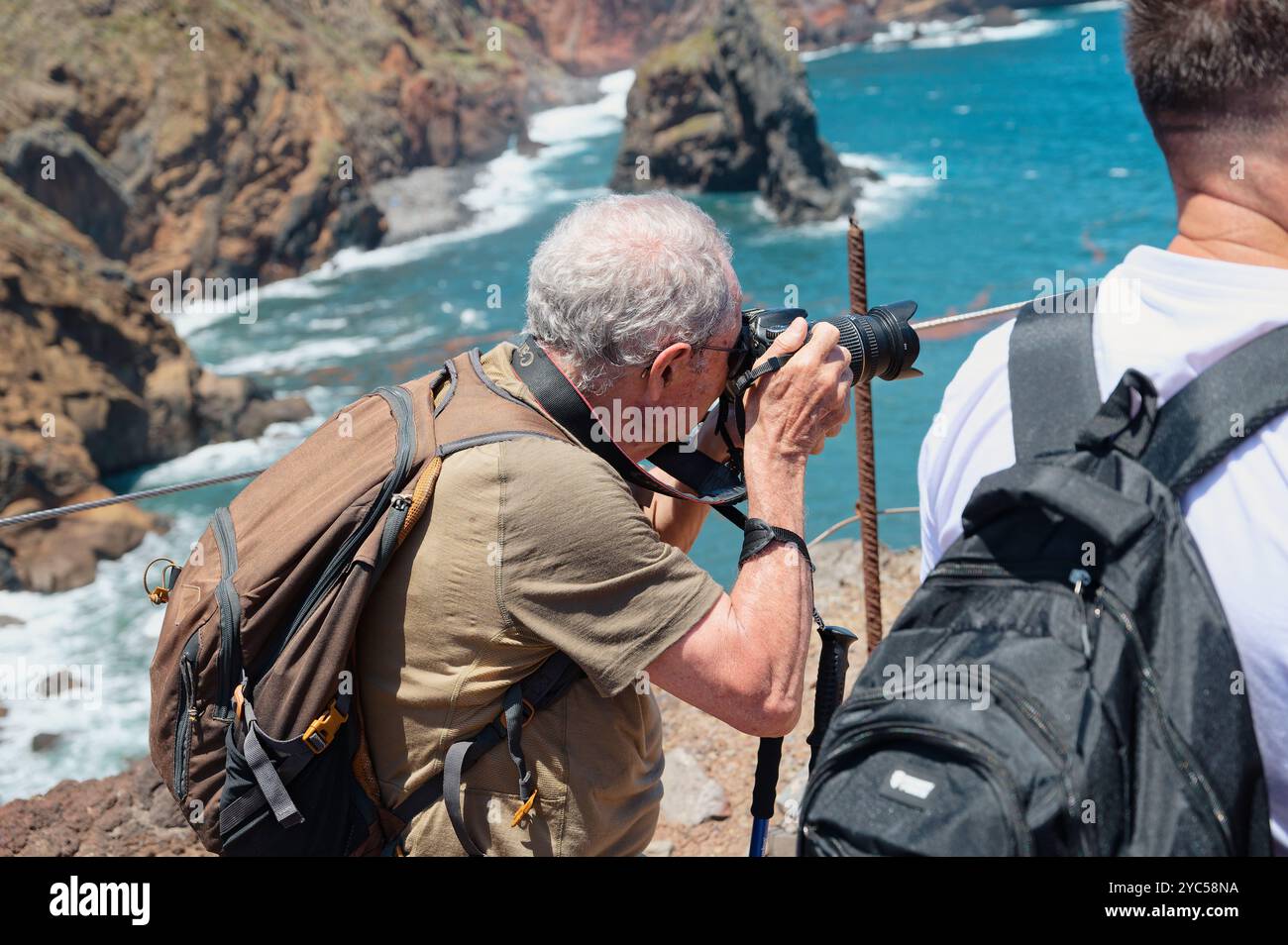 Ein reifer Fotograf, der die dramatische Küstenlandschaft von Vereda da Ponta de São Lourenco mit Klippen und dem Atlantischen Ozean im Hintergrund einfängt Stockfoto