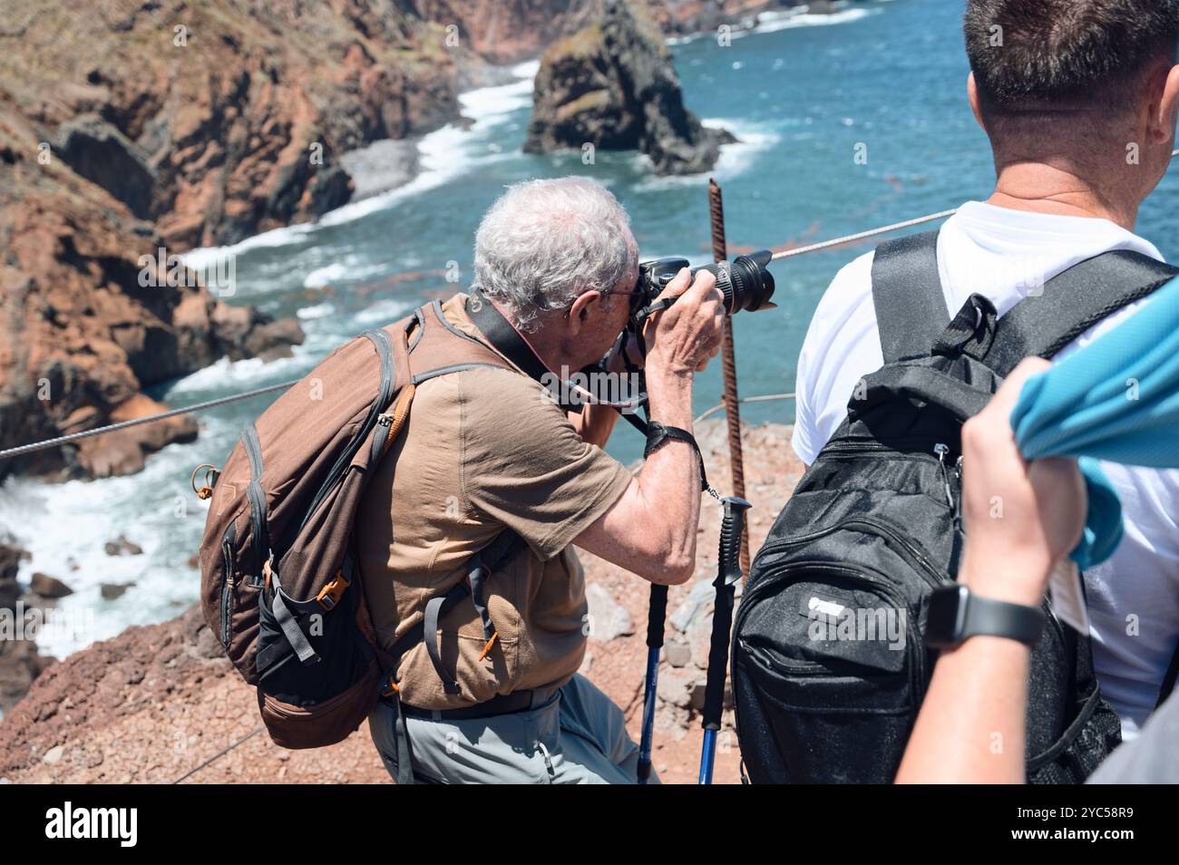 Ein reifer Fotograf, der die dramatische Küstenlandschaft von Vereda da Ponta de São Lourenco mit Klippen und dem Atlantischen Ozean im Hintergrund einfängt Stockfoto