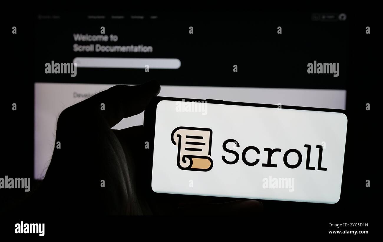 Person, die ein Smartphone mit dem Logo der Blockchain-Firma Scroll Foundation (Scroll.io) auf dem Bildschirm vor der Website hält. Schwerpunkt auf dem Display des Telefons. Stockfoto