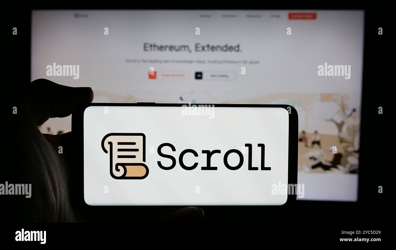 Person, die ein Mobiltelefon mit dem Logo der Blockchain-Firma Scroll Foundation (Scroll.io) auf dem Bildschirm vor der Webseite hält. Schwerpunkt auf dem Display des Telefons. Stockfoto