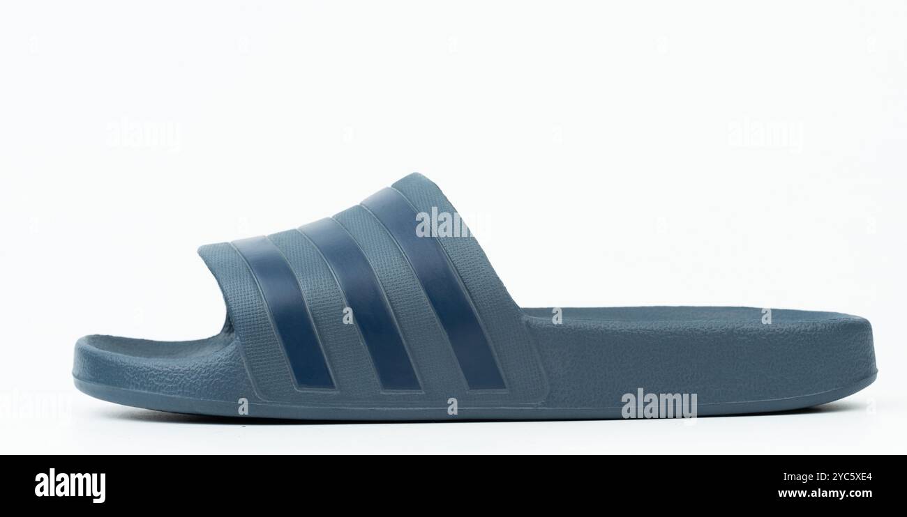 Gezeigt wird eine lässige blaue Slide-Sandale ohne Schnürsenkel, die für Tragekomfort und einfaches Tragen konzipiert ist. Stockfoto