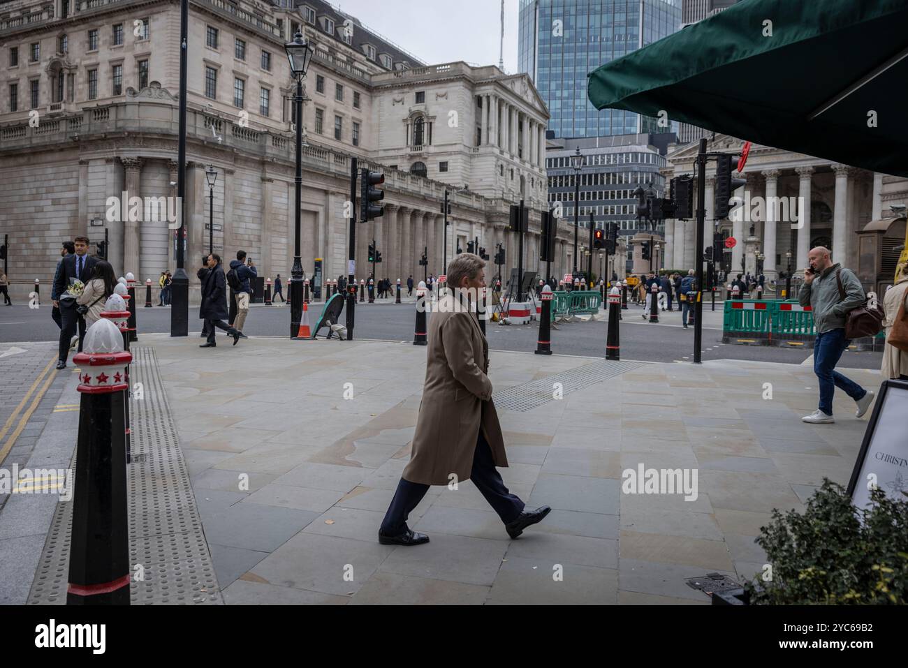 Geschäftsmann, der in der City of London arbeitet, läuft mit einem langen Wintermantel durch die Bank, während die Bank of England in der Ferne in London, Großbritannien, ist Stockfoto