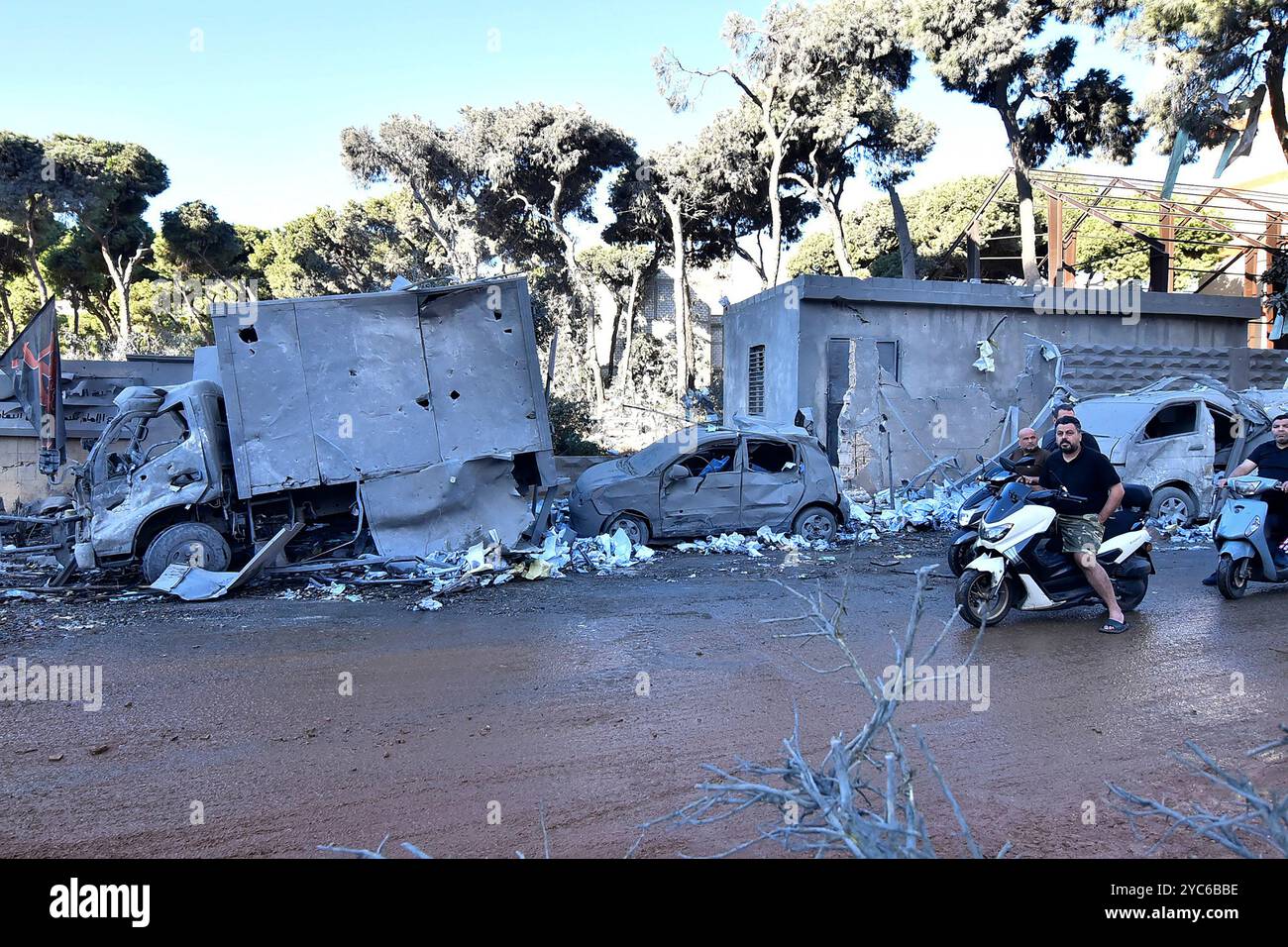 Beirut, Libanon. Oktober 2024. Libanesische Männer fahren mit dem Motorrad neben zerstörten Autos, nach einem nächtlichen israelischen Luftangriff in Baalbek im Südlibanon am Montag, den 21. Oktober 2024. Sechs Frauen und Kinder derselben Familie wurden bei einem israelischen Drohnenangriff auf die Nachbarschaft Nabi Anam in Baalbek im östlichen Libanon getötet und acht weitere verletzt. Foto: Fadel Itani/UPI Credit: UPI/Alamy Live News Stockfoto
