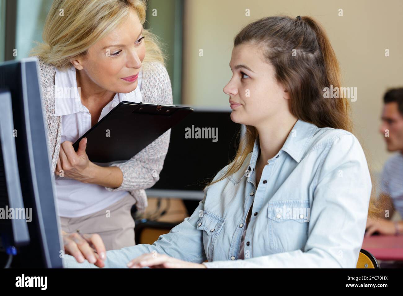 Reife Lehrerin hilft Jugendlichen Schülern mit Computer Stockfoto