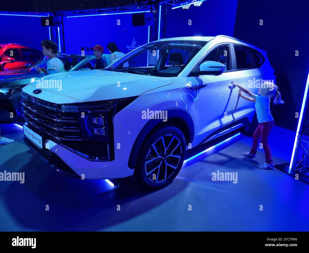 Kleines Mädchen, das versucht, die Tür eines weißen Moskwitsch 8 Autos zu öffnen, russisches Auto - Smartphone-aufgenommenes Stockfoto