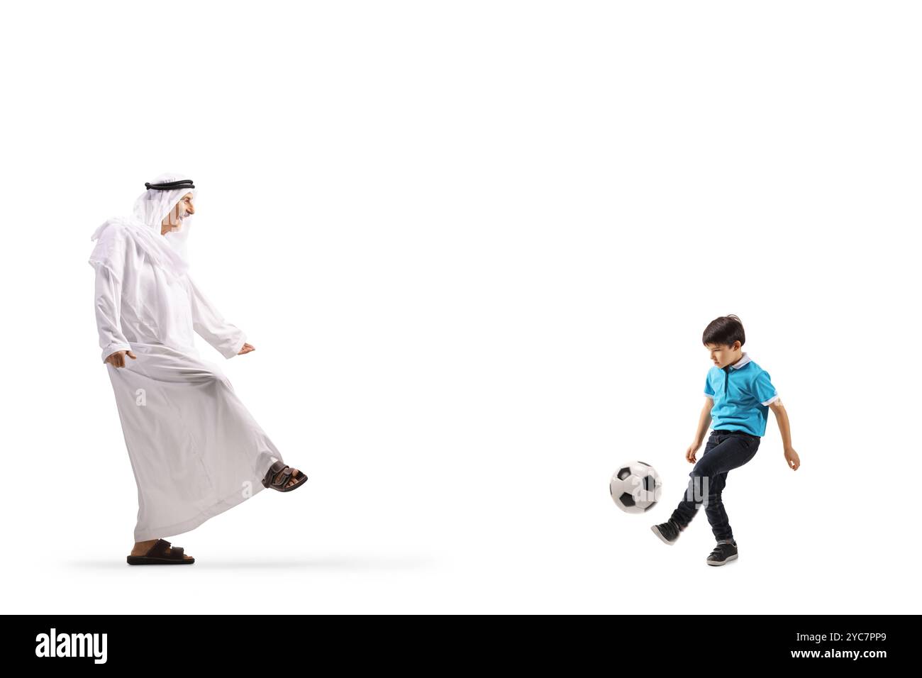 Arabischer Mann in ethnischer Kleidung, der mit einem Jungen auf weißem Hintergrund Fußball spielt Stockfoto