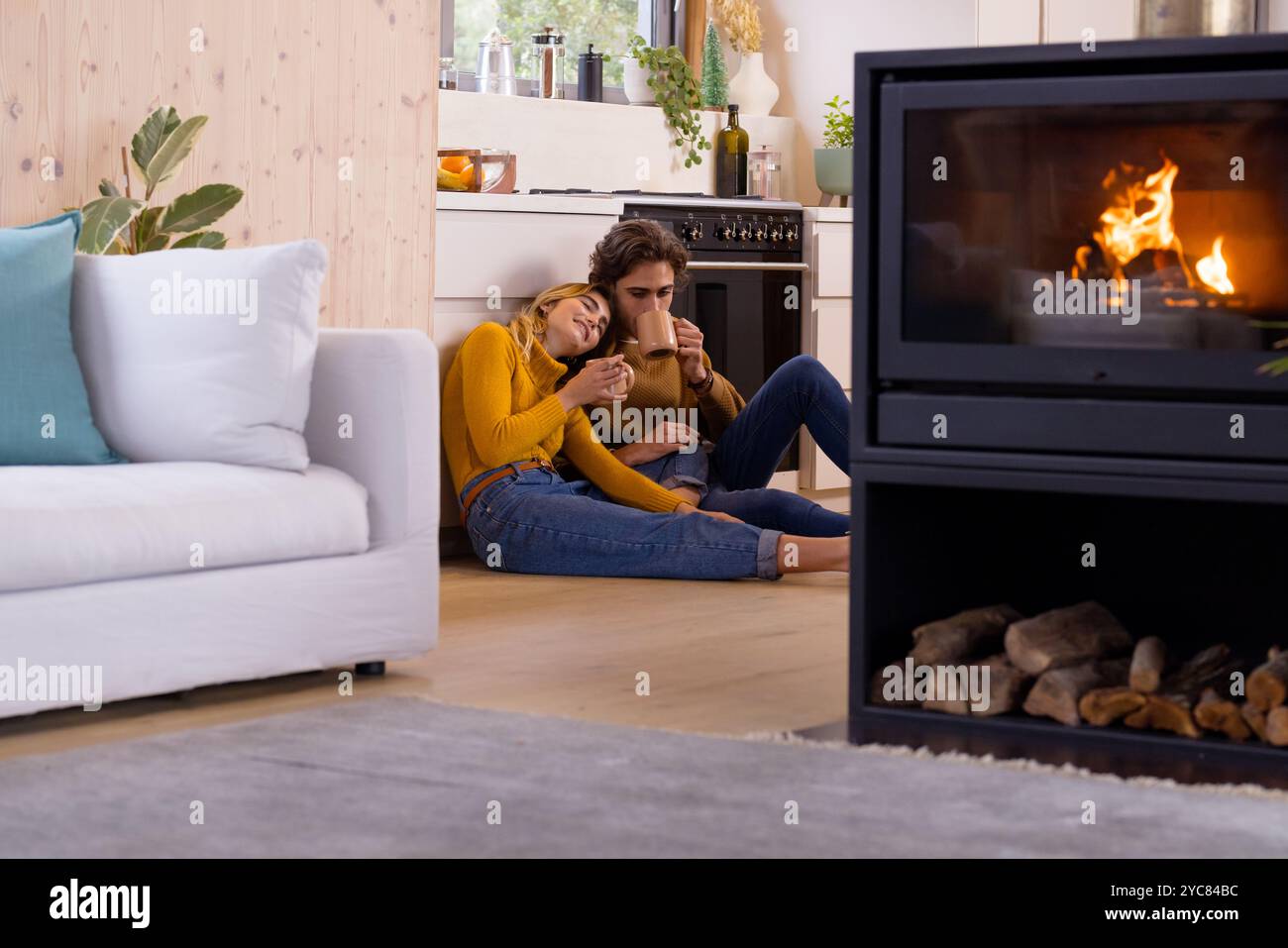 Gemütliches Paar genießt heiße Getränke am Kamin in warmer, festlicher Atmosphäre Stockfoto