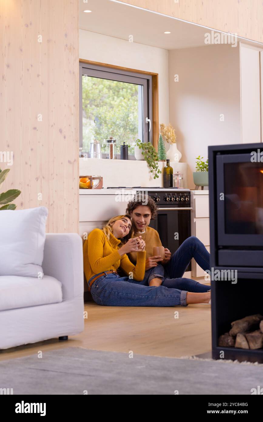 Paare entspannen sich am Kamin, genießen heiße Getränke in der gemütlichen Küche Stockfoto
