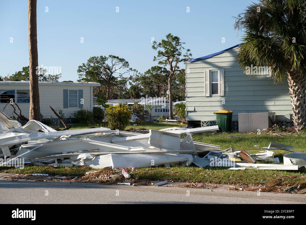 Müllhaufen auf der Straßenseite von stark beschädigten Häusern nach dem Hurrikan in Florida Wohnmobilgebiet. Folgen von Naturkatastrophen Stockfoto