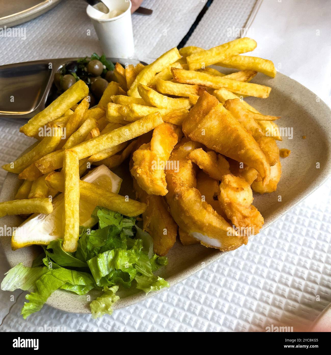 Traditionelle Tintenfischfinger, genannt Choco Frito, serviert mit Kartoffelchips oder Pommes frites in einem beliebten Restaurant von Setubal. Stockfoto