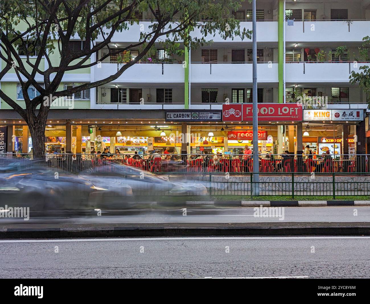 Abendliche urbane Szene mit lebhaften Straßenaktivitäten und beleuchteten Imbissständen. Stockfoto