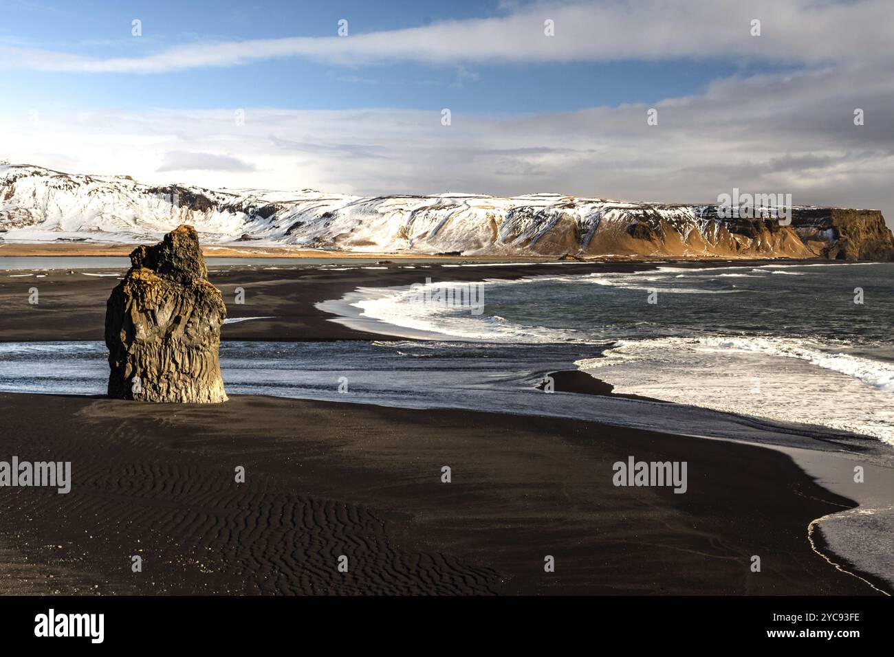 Landschaft mit schwarzem Sand, schneebedeckten Bergen und Felsen im Meer, Kirkjufjara, Island, Europa Stockfoto