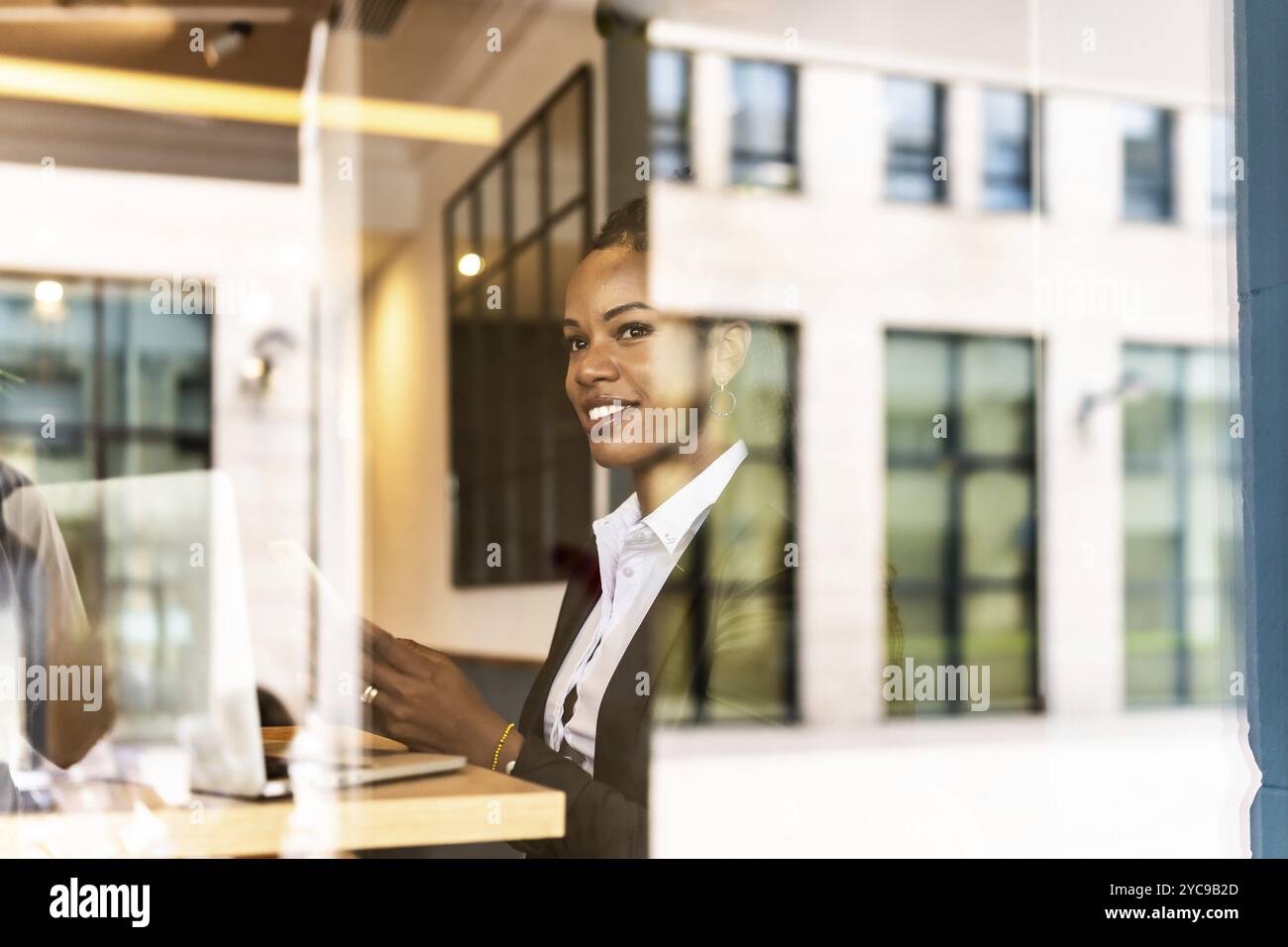 Blick aus dem Fenster einer abgelenkten Geschäftsfrau, die ihr Mobiltelefon benutzt und in einer modernen Cafeteria im Finanzviertel arbeitet Stockfoto