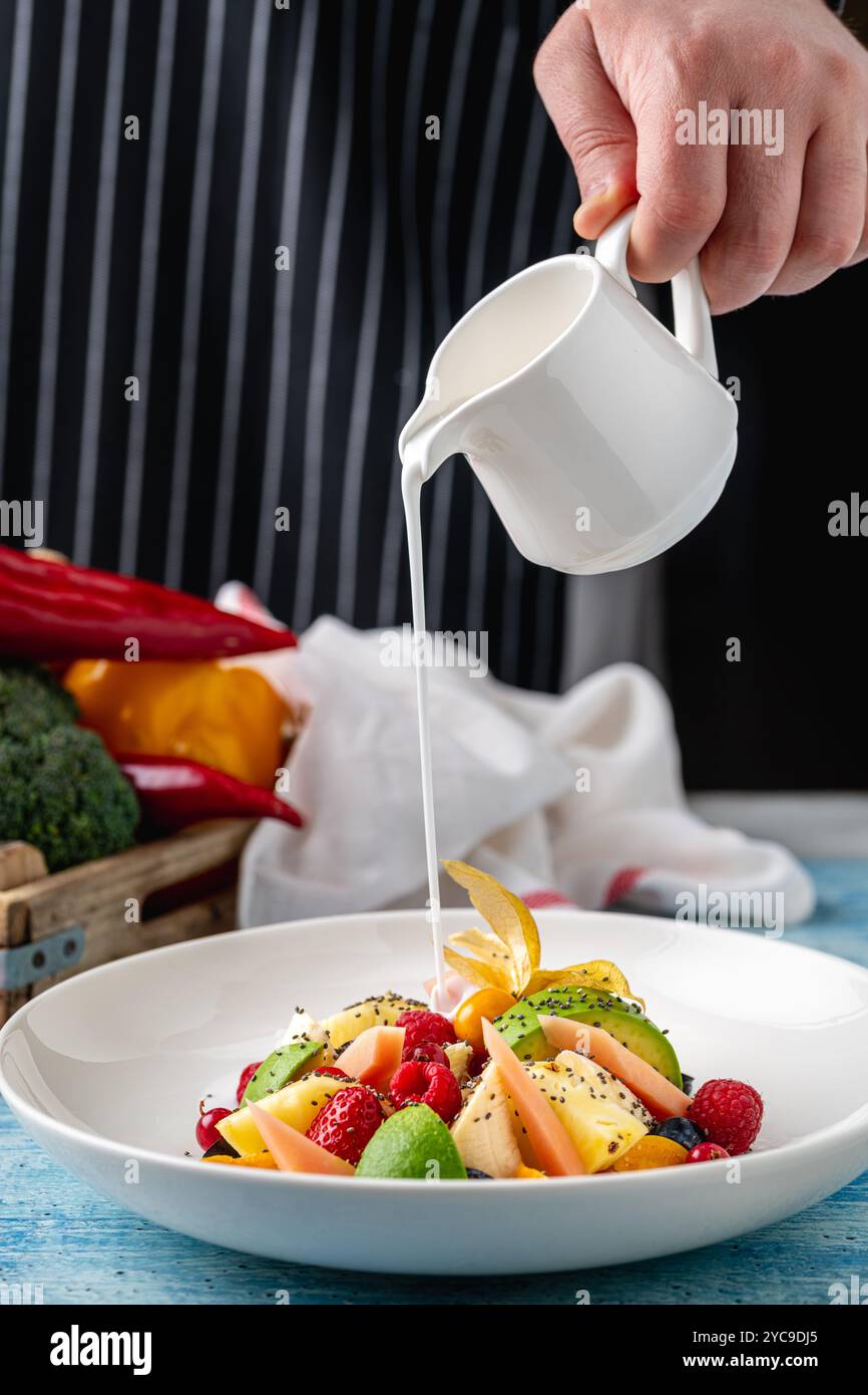 Gemischter Obstsalat mit Früchten wie Banane, Erdbeere und Ananas auf einer weißen Porzellanplatte Stockfoto