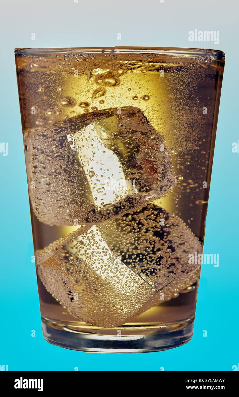 Glas kohlensäurehaltiges Getränk mit großen Eiswürfeln auf blauem Hintergrund. Stockfoto
