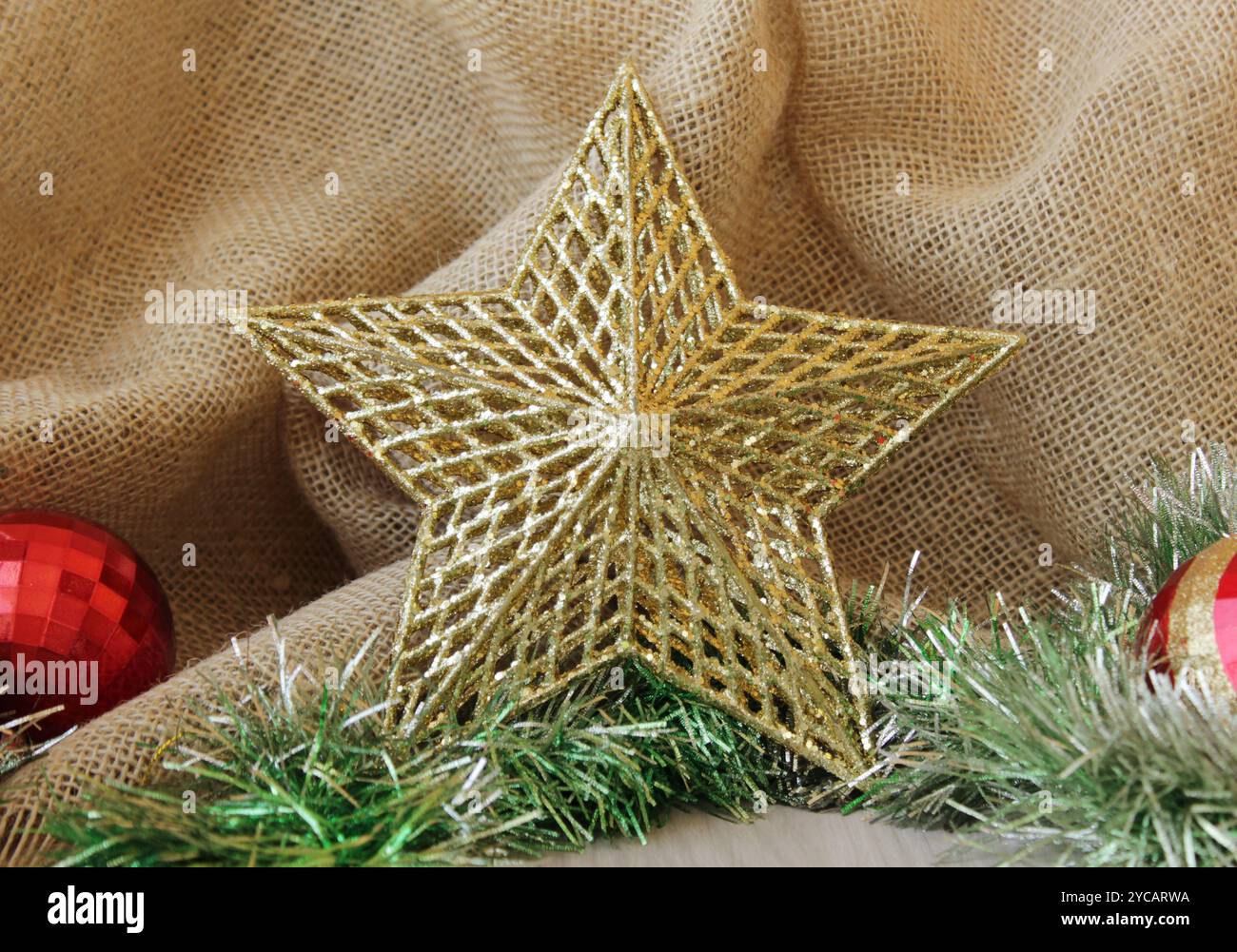 Goldener Glitzerstern vorne os Jute Stoff Hintergrund für Weihnachtsfeierlichkeiten. Weihnachtsdekoration für die Wintersaison. Stockfoto