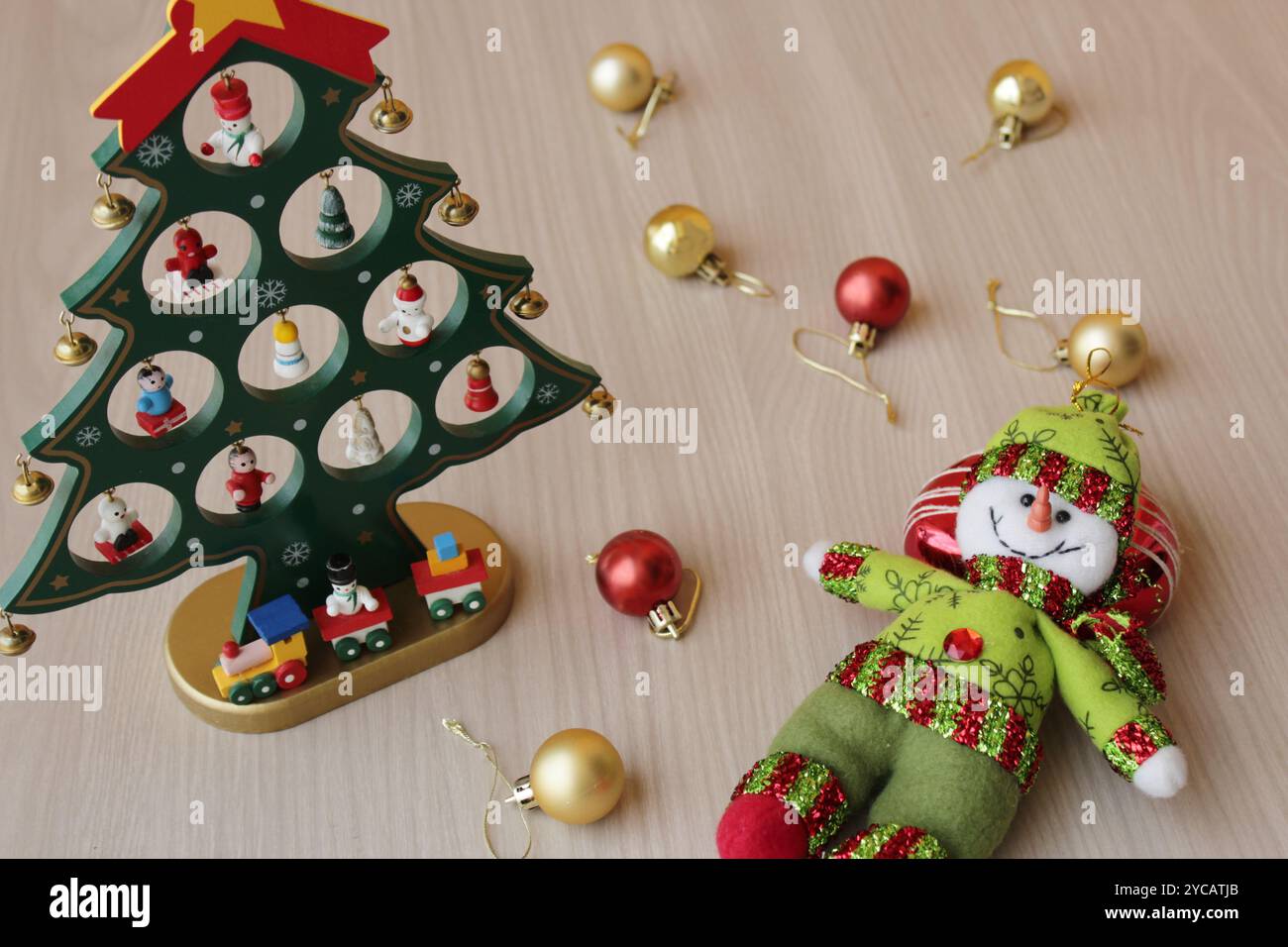 Gefüllter Schneemann und Weihnachtsbaumspielzeug auf Holzhintergrund für die Weihnachtsfeier im dezember. Weihnachtskugeln, Dekoration für die Wintersaison in Rot und Gold Stockfoto