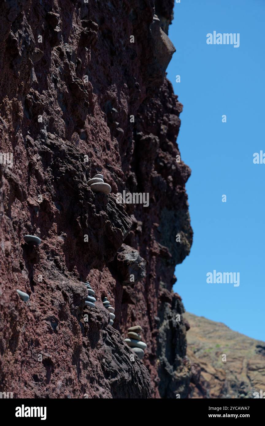 Kleine Steinstapel in den Spalten einer hohen roten Felsmauer bei Vereda da Ponta de São Lourenco Stockfoto