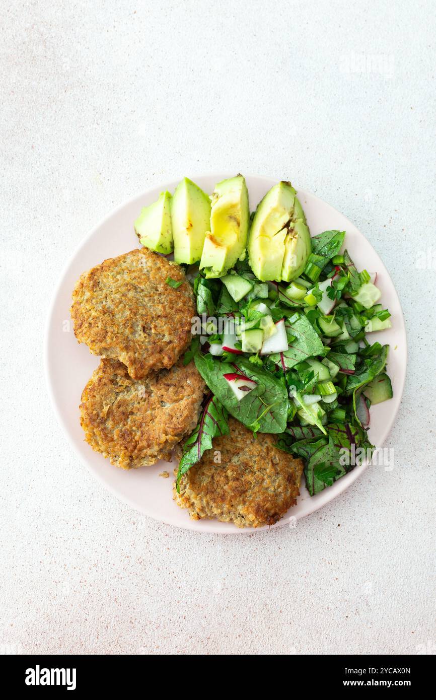 Quinoa-Schnitzel und gemischter Salat mit Avocado und Radieschen, Kiwi und Wasser mit Zitrone, köstliches herzhaftes Frühstück, veganer Lunch-Teller Stockfoto
