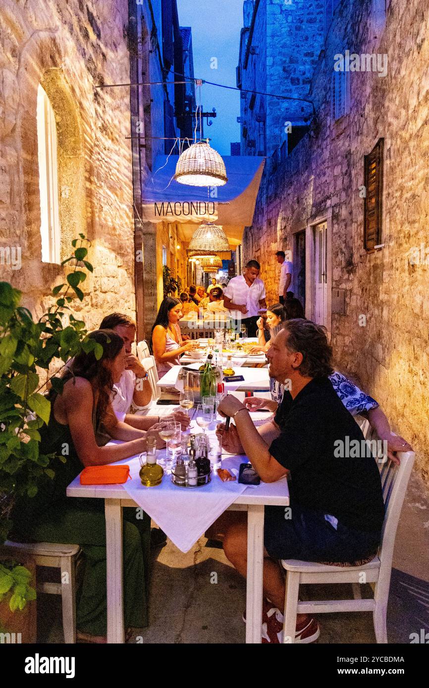 Die Leute essen im Freien in einer engen Straße im Macondo Restaurant auf der Insel Hvar, Kroatien Stockfoto