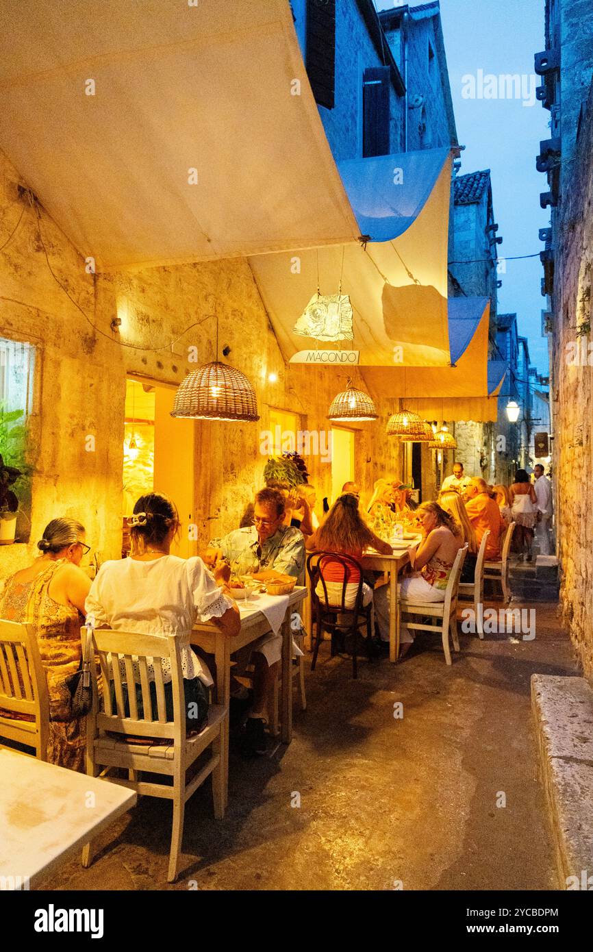 Die Leute essen im Freien in einer engen Straße im Macondo Restaurant auf der Insel Hvar, Kroatien Stockfoto
