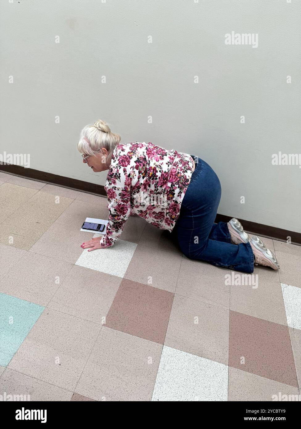Eine ältere Frau mit Schmerzen, die am ersten Tag der frühen Abstimmung auf die Wahl wartet, sitzt auf dem Flur und kriecht, während sich die Wahllinie bewegt. Wichita, Kansas, Stockfoto